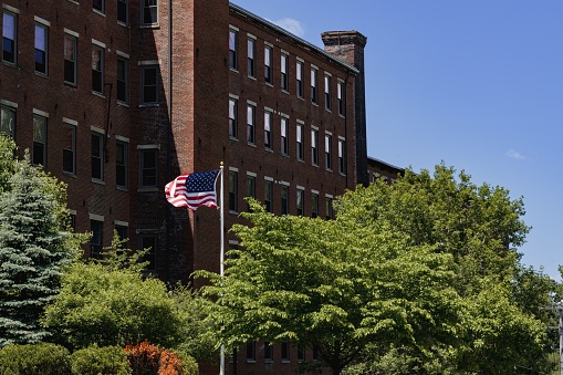 The United States flag waving in the wind with surrounded by trees and building