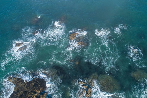 Aerial top view of waves on coastal rocks