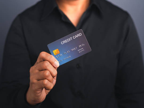 istock Businessman holding a mockup blue credit card while standing in a studio 1445357846