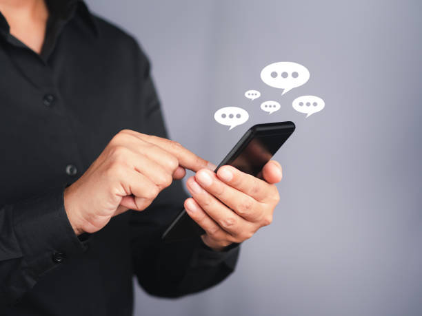 istock Businessman using a smartphone with an conversation icon while standing with a gray background 1445358711