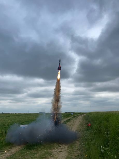 istock Vertical shot of a rocket flying from a green field to a cloudy sky 1445362908