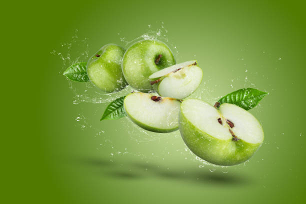 istock Water Splashing on Green apple and cut slice with seed on green background. 1445363928