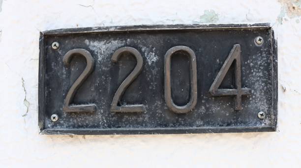 istock Close-up shot of a rustic metallic number 2204 on white wall background. 1445365953