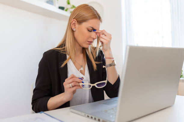 istock Feeling exhausted. Frustrated young woman looking exhausted while sitting at her working place and carrying her glasses in hand 1445366087