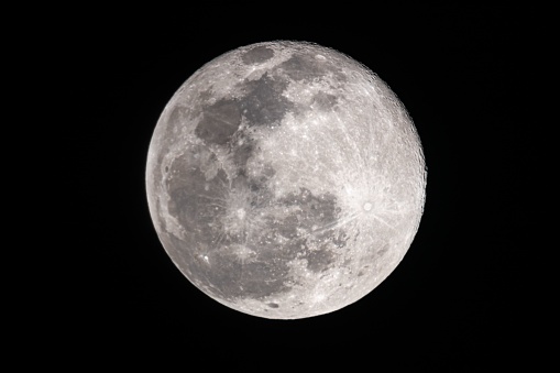 Close-up of the moon in the dark night sky. The moon is dotted with craters. Place for text