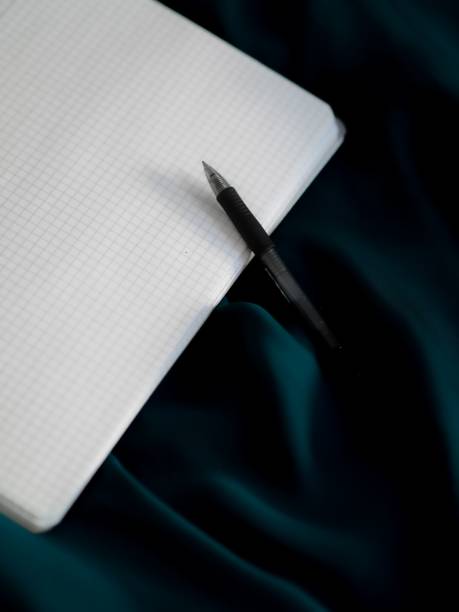 Pen and graphing paper on a shiny blue fabric surface