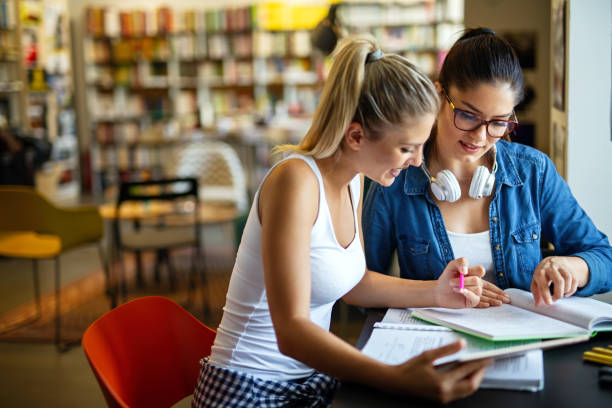 istock Happy young university students studying with books in library. 1445372092