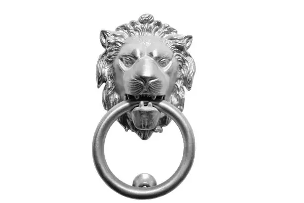 Head of a lion in silver color for knocking on a white door, isolated on a white background. Knocker in the form of a muzzle of a lion with a ring, close-up