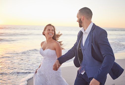 Couple, wedding and beach smile in sunset on romantic walk together after getting married. Happy, wife and man in suit walking, ocean, romance and marriage after ceremony with sun setting over sea