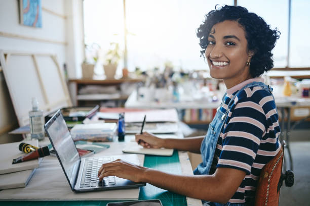 istock Creative black woman, smile and laptop working in art studio, workshop or design startup with notebook. Portrait of a happy African American female freelancer, designer or artist at work on computer 1445377307