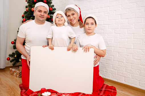 Family with banner. Group of happy people with banner. Group of happy people with banner. Happy family in Christmas clothes with blank poster. Family holding Christmas banner