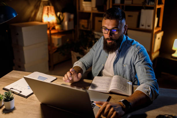 istock Businessman using his notes and typing data on laptop when staying late at the office 1445378926