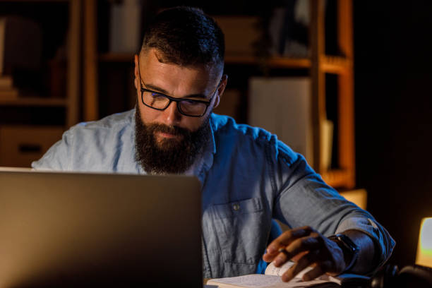 istock Businessman checking his notes and using laptop when staying late at the office 1445379019