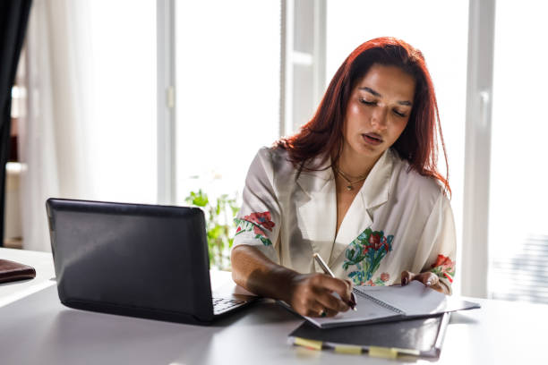 istock Businesswoman writing plans in a notebook at her desk 1445379718