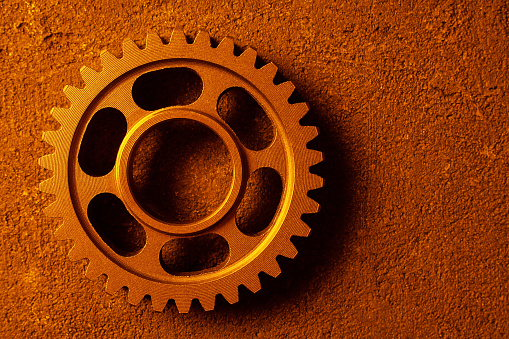 Three old gears on a striped dirty surface with blueprint in yellow. This image is a 3D render.