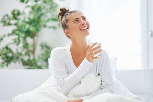 istock Young brunet woman relaxing on bed with water 1445381863