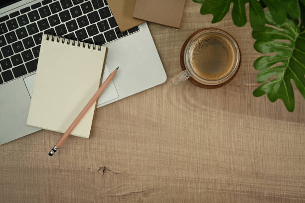 istock Laptop computer, notepad, coffee cup and houseplant on wooden table. Top view, flat lay with copy space. 1445382084