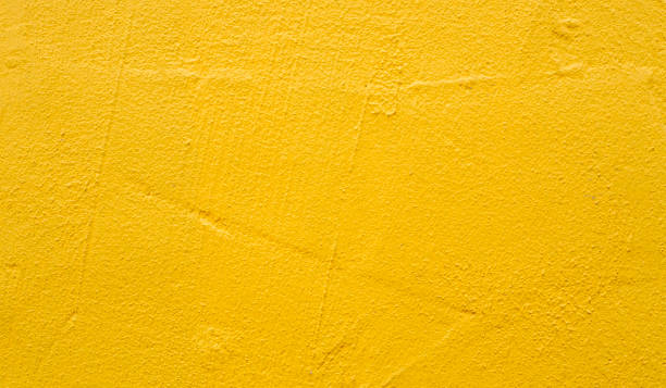 Rough blank wall painted by bright yellow paint as texture background or backdrop stock photo