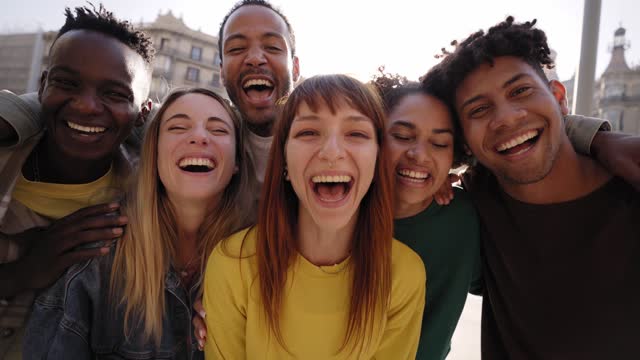 Young smiling happy looking at camera hugging. Group of multicultural friends having fun outdoors