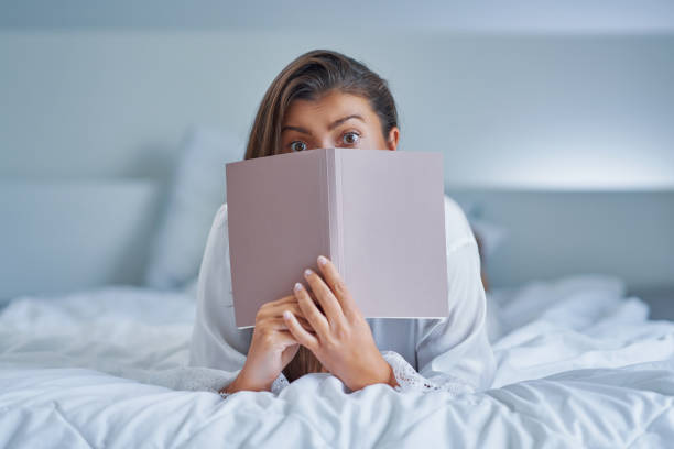 istock Brunette woman on bad with notepad or book 1445386112