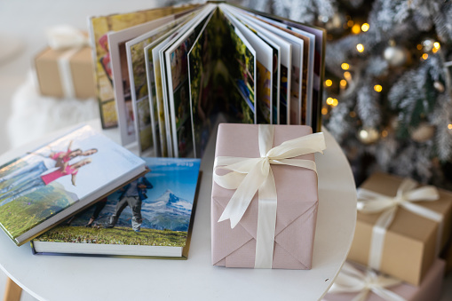 Photo book album under the Christmas tree surrounded by Christmas gifts.