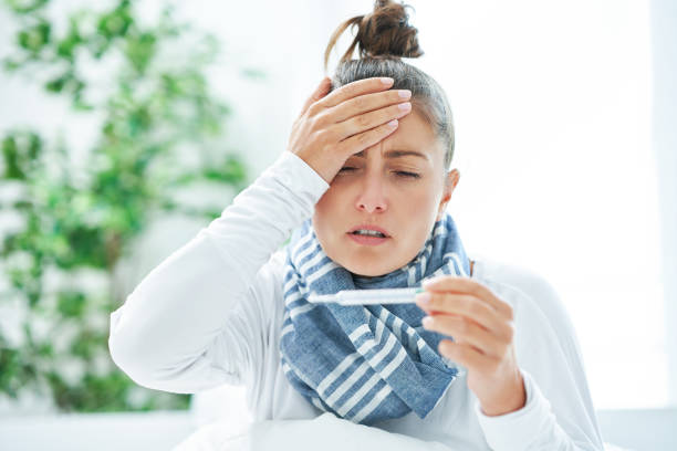 istock Young brunet woman sick in the bed with thermometer 1445387919