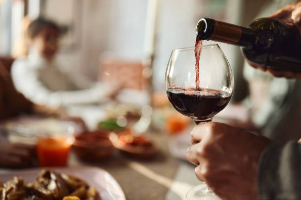 Pouring red wine! Close up of unrecognizable black man pouring red wine into a glass in dining room. wine stock pictures, royalty-free photos & images