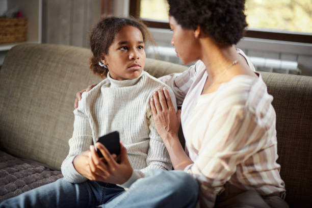Sad black girl talking to her single mother at home. Sad African American girl talking about her problems with her mother in the living room. kids and parents talk  stock pictures, royalty-free photos & images
