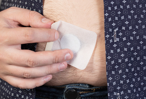 A modern medical patch for prostatitis and urinary tract infections. A man glues a urological patch on his stomach.
