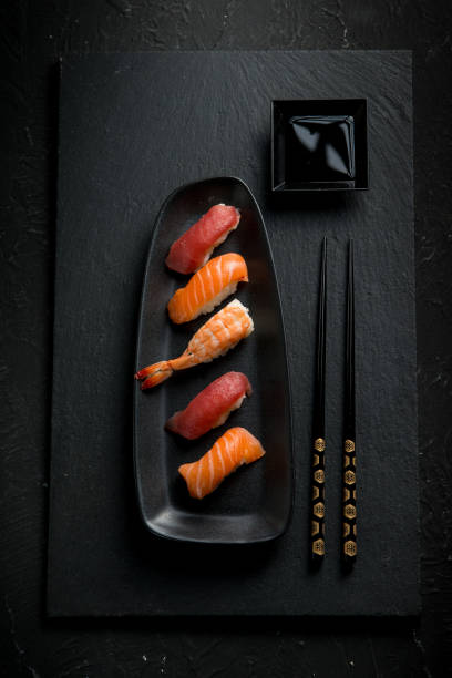 istock sushi with chopstick over black stone 1445392872