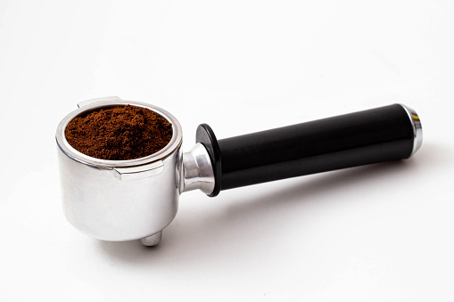 Barista preparing ground coffee with an espresso tamper in a portafilter
