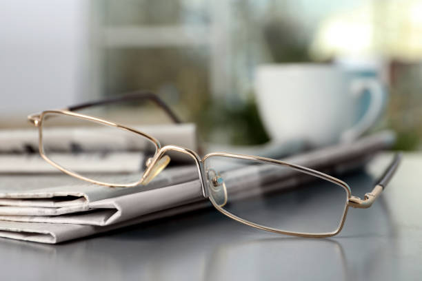 istock Stack of newspapers and glasses on grey table indoors, closeup 1445393108