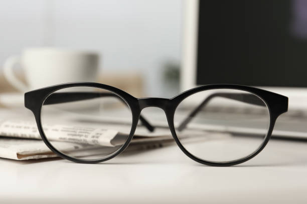 Newspapers and glasses on white table indoors, closeup