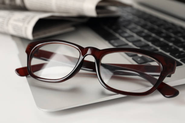 istock Modern laptop and glasses on white table, closeup 1445393480