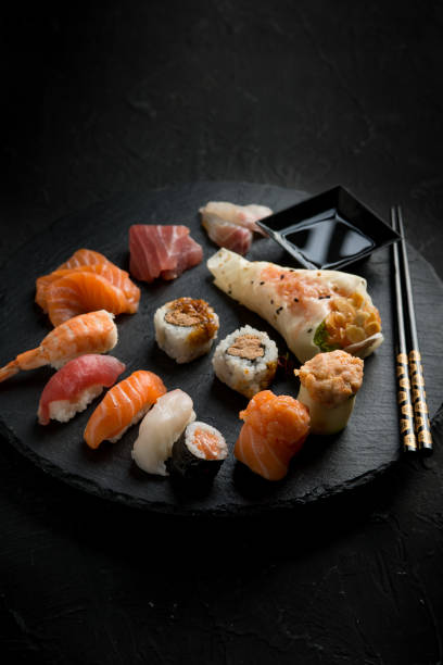 istock sushi mix with chopstick over black stone 1445393527