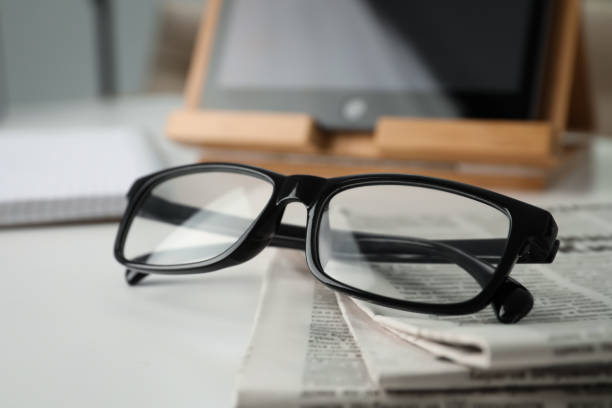 istock Stack of newspapers and glasses on white table indoors, closeup 1445393598