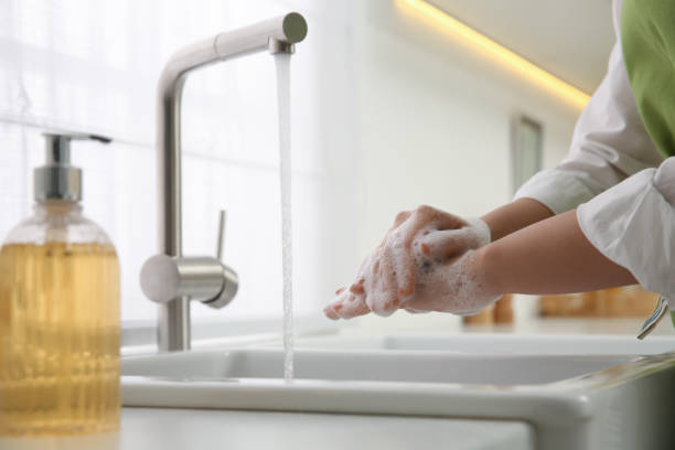 istock Woman washing hands with liquid soap in kitchen, closeup 1445394402