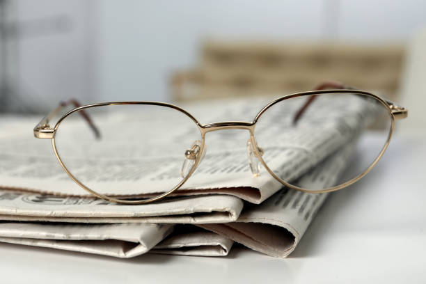 istock Stack of newspapers and glasses on white table indoors, closeup 1445394457