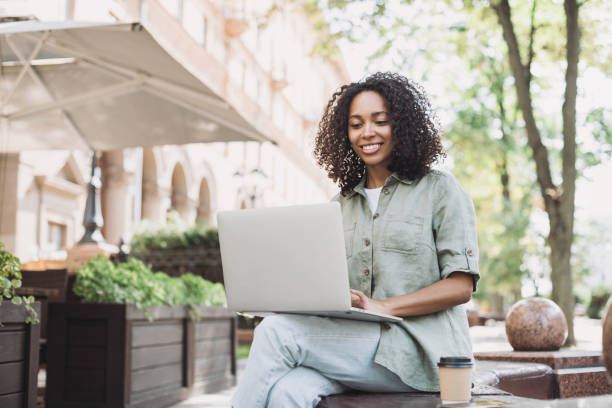 istock Happy woman using laptop in a city 1445394694