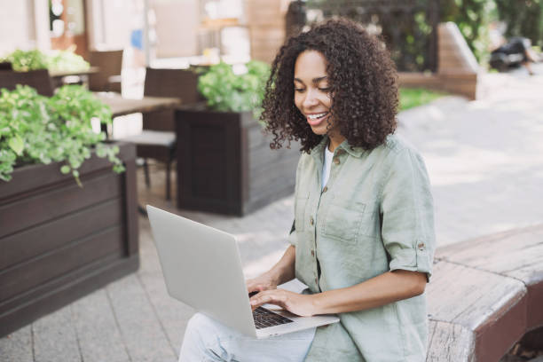 istock Happy woman using laptop in a city 1445394696