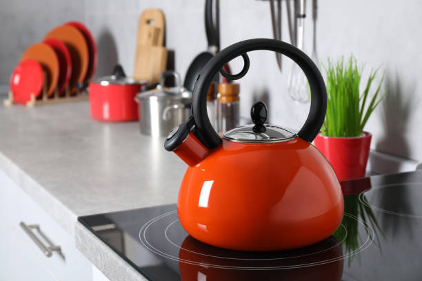 Red kettle on electric stove in kitchen, space for text