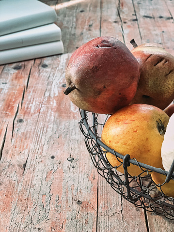 Close-up of autumn fruits in wire basket on weathered wooden table