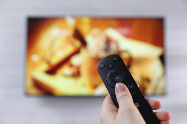 istock Woman with remote control watching TV at home, closeup. Space for text 1445396324