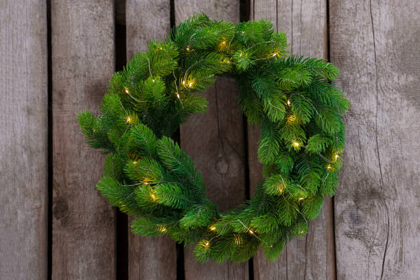 istock Beautiful Christmas wreath with string lights hanging on wooden wall 1445396935