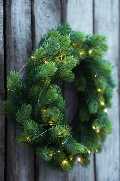 istock Beautiful Christmas wreath with string lights hanging on wooden wall 1445396973