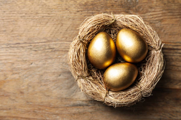 istock Nest with golden eggs on wooden table, top view. Space for text 1445398221
