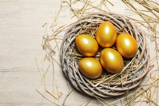 istock Nest with golden eggs on white wooden table, flat lay. Space for text 1445398424