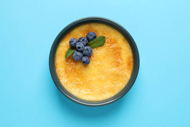 deliziosa crema catalana con mirtilli freschi e menta su sfondo azzurro, vista dall'alto - brule foto e immagini stock