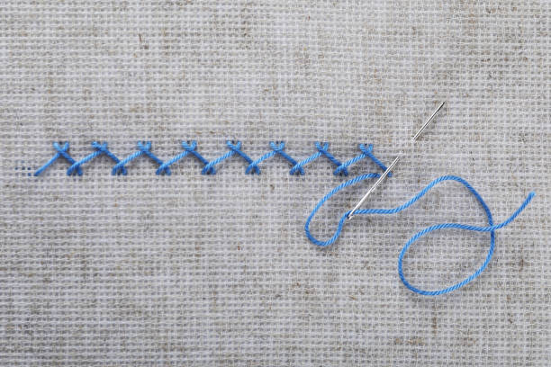 istock Embroidery stitches made with light blue thread and needle on canvas, top view 1445401005