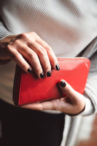 istock Black painted nails on woman's hand holding wallet 1445402180
